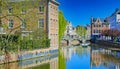 View over village water moat on ancient buildings, medieval stone arch bridge, blue sky