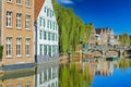 View over village water moat on ancient buildings, medieval stone arch bridge, blue sky Royalty Free Stock Photo