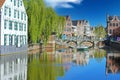 View over village water moat on ancient buildings, medieval stone arch bridge, blue sky Royalty Free Stock Photo