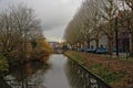 Lieve canal with bare trees and an old medieval bridge in the distance in Ghent