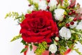 Life-affirming composition of fresh flowers Rose, Eustoma, Solidaga, Pistachio leaves and decorative berries in a scarlet cardbo