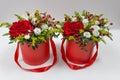 Life-affirming composition of fresh flowers Rose, Eustoma, Solidaga, Pistachio leaves and decorative berries in a scarlet cardbo