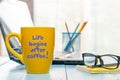 Life begins after coffee - inscription on yellow morning coffee cup at businessman workplace Royalty Free Stock Photo