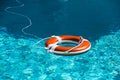 Life buoy in blue swimming pool. Lifebuoy pool ring float on blue water. Royalty Free Stock Photo