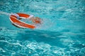 Life buoy in blue swimming pool. Lifebuoy pool ring float on blue water. Royalty Free Stock Photo