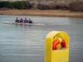 Life buoy bright yellow holder n focus, men team of four on a canoe in a river out of focus, concept safety and water sports