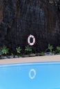 Life buoy hanging on dark rocky wall at pool Royalty Free Stock Photo