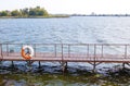 Life buoy hanging on the pier bridge near the water Royalty Free Stock Photo