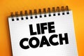 Life Coach - type of wellness professional who helps people make progress in their lives, text concept on notepad