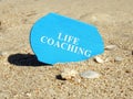 Life coaching sign on a plank in sand.