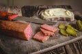Sliced rectangular smoked sausage, pickles and bread with sausage on an old wooden table. Eye level shooting. Soft focus. Royalty Free Stock Photo
