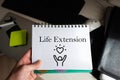 Life extension word on notebook holding man against desktop