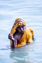 Life on the Ganges: woman in a bright yellow or orange sari bathing in the Ganges as religious ritual. beautiful color contrasts