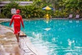 Life guard wearing red uniform working/walking around poolside keeping an eye on things at public pool in Asia