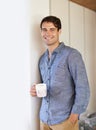 Life happens after coffee. Portrait of a young man leaning against a wall while holding a cup of coffee.