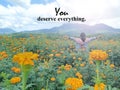 Life inspirational motivational quote - You deserve everything. With woman standing on marigold garden with raised hands.