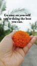 Life inspirational quote - Go easy on yourself, you're doing the best you can. Person holding orange marigold flower in hand