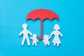 Life insurance concept. Paper cutout of family father, mother, son and daughter under red umbrella on blue background. Royalty Free Stock Photo