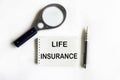 Life insurance word on notepad with magnifying glass and pen Royalty Free Stock Photo
