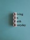 LIFE living in faith everyday symbol. Concept words LIFE living in faith everyday on wooden cubes on blue background Royalty Free Stock Photo