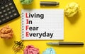 LIFE living in fear everyday symbol. Concept words LIFE living in fear everyday on note on a beautiful yellow background. Black Royalty Free Stock Photo