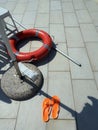 Lifeguard equipment, orange lifebelt with rope hang on the wall near the swimming pool