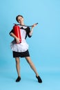 Full-length portrait of young Caucasian woman in black uniform with fire extinguisher isolated over blue background Royalty Free Stock Photo