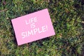 Life is simple quote written on paper on green grass background. Peaceful, comfortable and simplified life concept