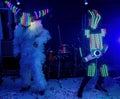 Life-size puppets in the form of robots on a stage. Funny amateur dance