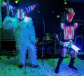 Life-size puppets in the form of robots on a stage. Funny amateur dance