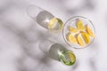 Life style photo with bright glass cups with fresh water and plate with citrus of lemon on white background