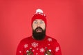 Life is surprising. Bearded face close up red background. Winter holidays. Man hipster wear winter knitted hat