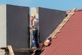 Life-threatening high-altitude work. A team of roofers works on the roof without insurance. Repair of the roof and ventilation Royalty Free Stock Photo