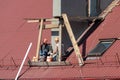 Life-threatening high-altitude work. A team of roofers works on the roof without insurance. Repair of the roof and ventilation Royalty Free Stock Photo