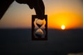 Life time passing concept. Hand holding hourglass with sunset sky background. Royalty Free Stock Photo