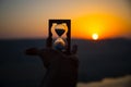 Life time passing concept. Hand holding hourglass with sunset sky background. Royalty Free Stock Photo