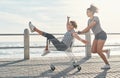 Life would be so boring without friends. a young woman pushing her friend around on the promenade in a shopping chart.