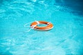 Lifebelt on sea or pool. Orange inflatable ring floating in blue water. Life buoy for protect and safety drowning.