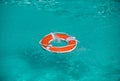 Lifebelt on sea or pool. Orange inflatable ring floating in blue water. Life buoy for protect and safety drowning. Royalty Free Stock Photo