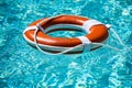Lifebelt on sea or pool. Orange inflatable ring floating in blue water. Life buoy for protect and safety drowning. Royalty Free Stock Photo