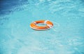 Lifebelt on sea or pool. Orange inflatable ring floating in blue water. Life buoy for protect and safety drowning. Royalty Free Stock Photo
