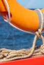 A lifebuoy is attached to a bright orange wooden frame with linen ropes