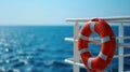 lifebuoy attached to a ship\'s white railing, with the clear blue sea in the background