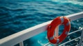 lifebuoy attached to a ship\'s white railing, with the clear blue sea in the background