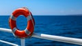 lifebuoy attached to a ship\'s white railing, with the clear blue sea in the background