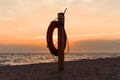 Lifebuoy on the beach against the background of an orange sunset over the sea Royalty Free Stock Photo
