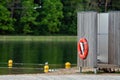 Lifebuoy by the changing cabin on the shore of the river with trees in the background