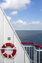 Lifebuoy and part of ship at sea with blue sky and clouds