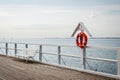 Lifebuoy at pier with empty bench in Gdynia Orlowo, Poland Royalty Free Stock Photo