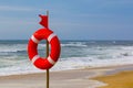 Lifebuoy and red warning flag flapping in the wind on the beach at storm. A symbol of the deterioration of the weather Royalty Free Stock Photo